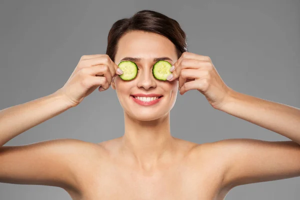 Hermosa mujer haciendo máscara de ojos de pepinos — Foto de Stock