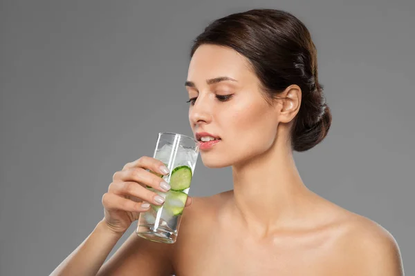 Frau trinkt Wasser mit Gurke und Eis — Stockfoto