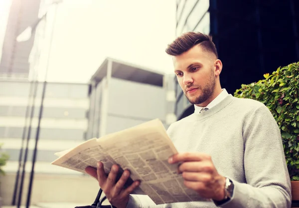 Mann liest Zeitung auf Stadtbank — Stockfoto