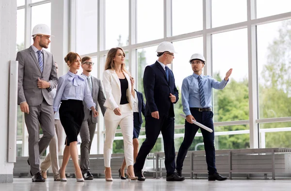 Equipe de negócios em capacetes andando ao longo do escritório — Fotografia de Stock