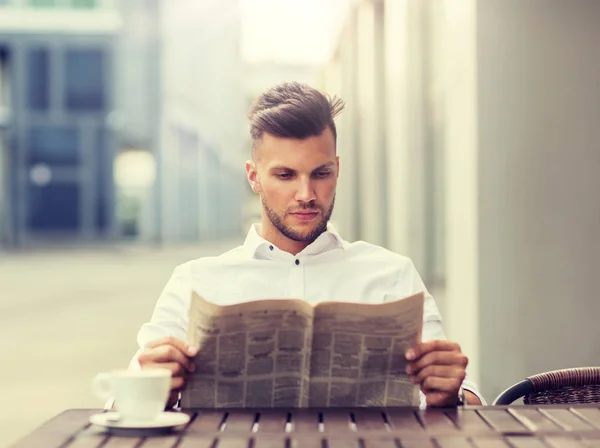 Sonriente hombre leyendo el periódico en la ciudad café de la calle —  Fotos de Stock