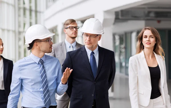 Business team in helmen wandelen langs office — Stockfoto