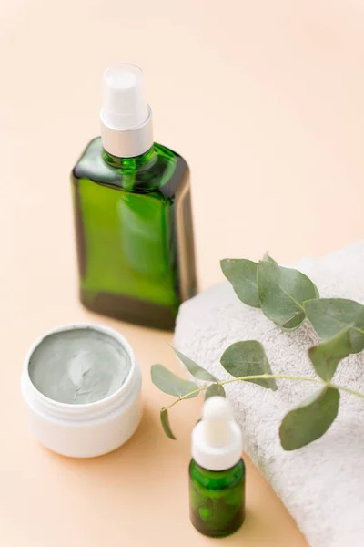 Serum, kleimasker, olie en eucalyptus op badhanddoek — Stockfoto