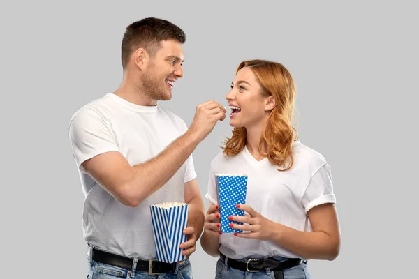 Happy couple in white t-shirts eating popcorn — Stock Photo, Image
