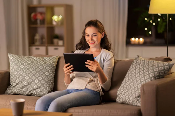Mujer feliz con la tableta PC en casa por la noche —  Fotos de Stock