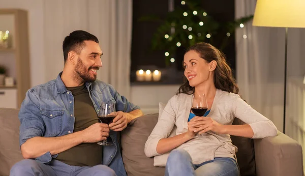 Feliz pareja bebiendo vino tinto en casa por la noche — Foto de Stock
