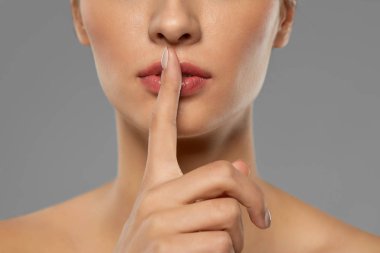 beautiful young woman holding finger on lips