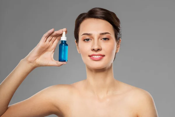 Beautiful young woman with bottle of serum — Stock Photo, Image