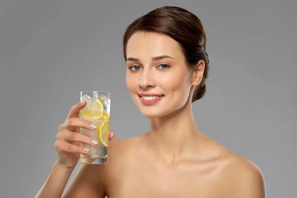Женщина пьет воду с лимоном и льдом — стоковое фото