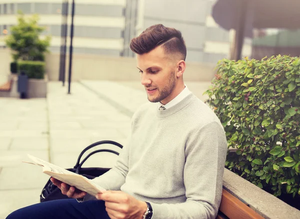 Sonriente hombre leyendo periódico en banco de la calle de la ciudad —  Fotos de Stock