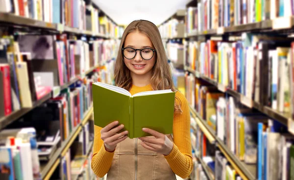 Estudante menina em óculos livro de leitura na biblioteca — Fotografia de Stock