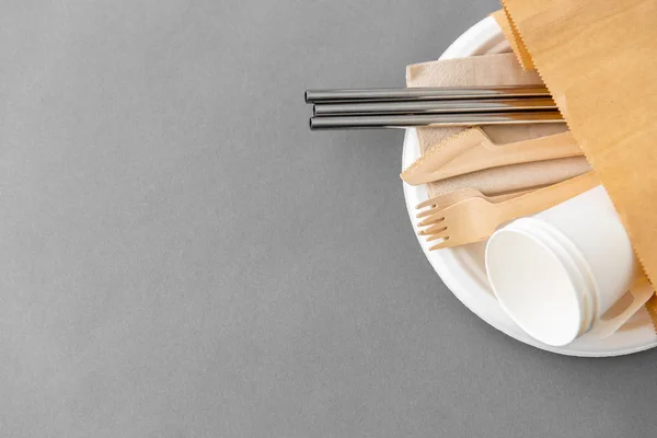 Wooden forks, knives and paper cups on plate — Stock Photo, Image