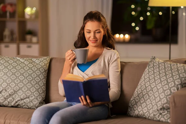 Mujer joven leyendo libro en casa por la noche —  Fotos de Stock