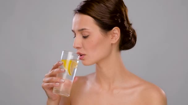 Frau trinkt frisches Wasser mit Zitronenscheiben — Stockvideo