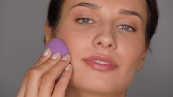 Jovem com esponja aplicando maquiagem — Vídeo de Stock