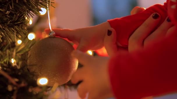 Руки младенца касаются шара висящего на рождественской елке — стоковое видео