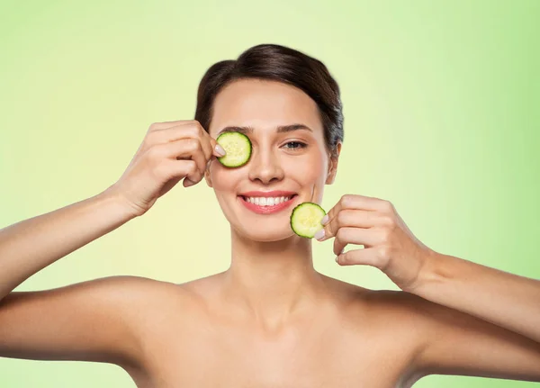 Hermosa mujer haciendo máscara de ojos de pepinos — Foto de Stock