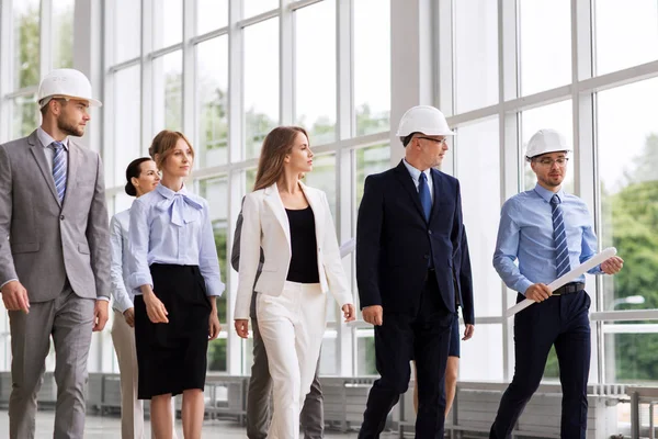 Business-team i hjälmar promenader längs office — Stockfoto