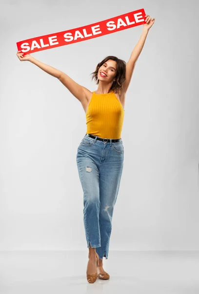 Feliz joven sonriente posando con la bandera de la venta — Foto de Stock