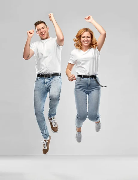 Feliz pareja en blanco camisetas saltar — Foto de Stock