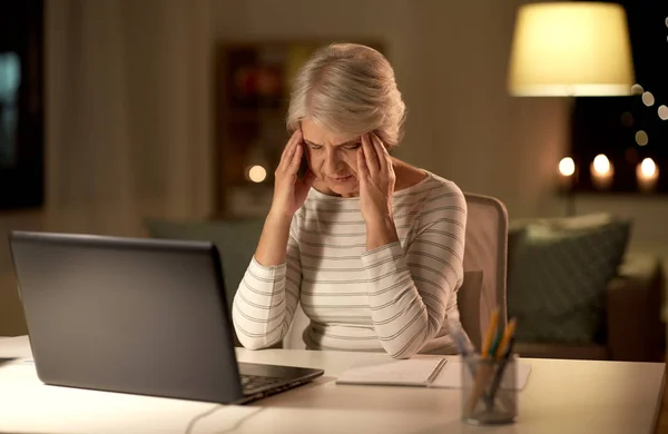 Втомлена старша жінка з ноутбуком вдома вночі — стокове фото