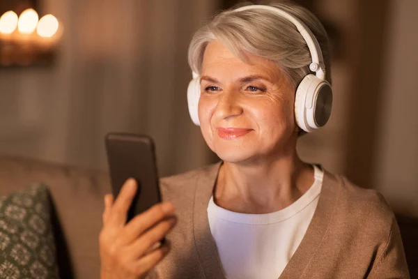 Mulher idosa em fones de ouvido ouvindo música — Fotografia de Stock