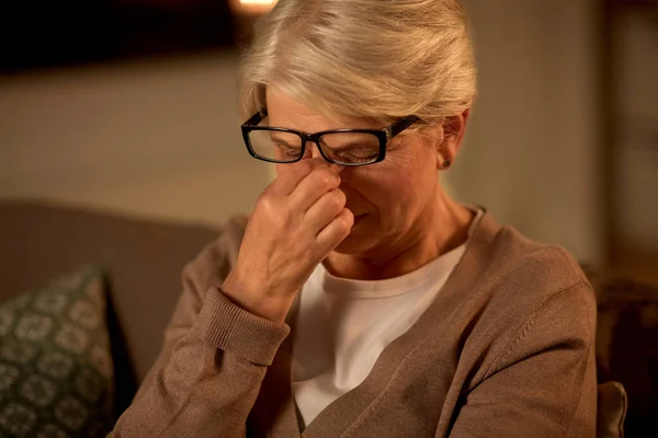 Tired senior woman in glasses at home at night — Stock Photo, Image