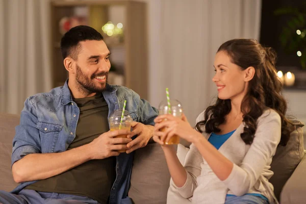 Casal feliz beber suco takeaway em casa — Fotografia de Stock