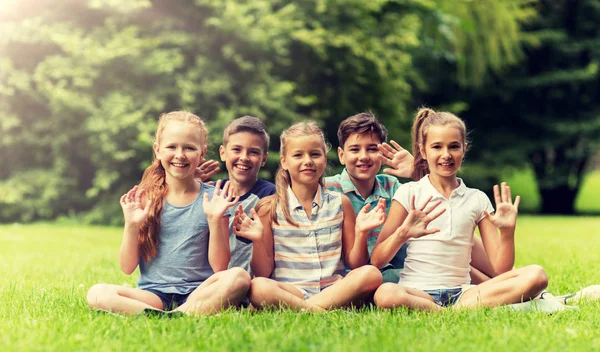 Groep gelukkige jonge geitjes zwaaien handen buitenshuis — Stockfoto