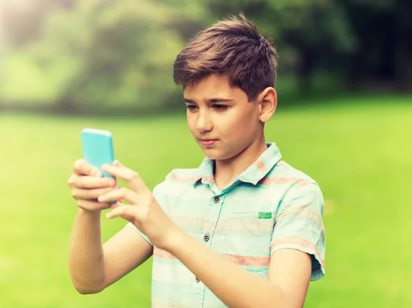 Хлопчик зі смартфоном грає в гру в літньому парку — стокове фото