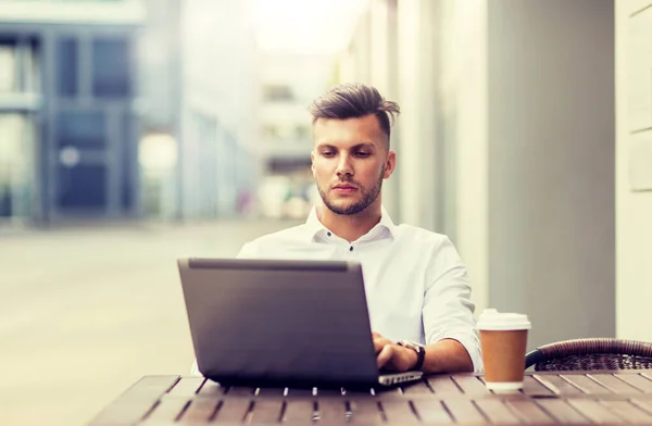 Homme avec ordinateur portable et café au café de la ville — Photo