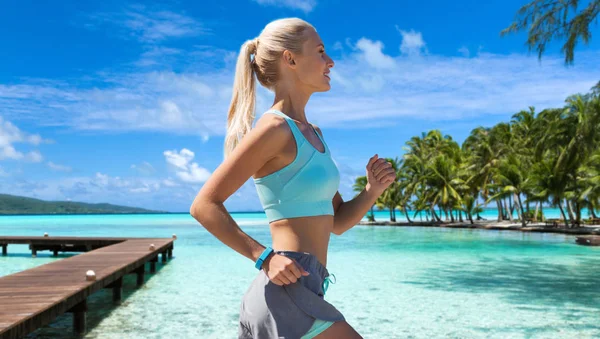 Usmívající se mladá žena běží podél exotické pláže — Stock fotografie