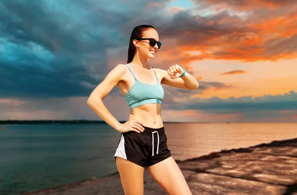 Happy woman with fitness tracker on summer beach — Stock Photo, Image