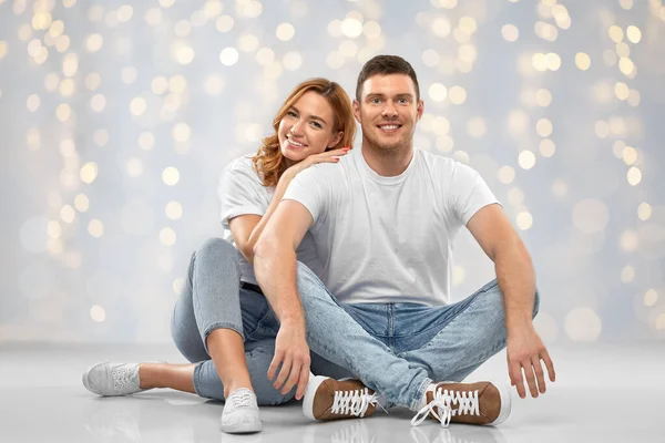 하얀 티셔츠를 입고 바닥에 앉아 있는 행복 한 커플 — 스톡 사진