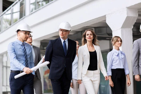 Business team in helmets walking along office — Stock Photo, Image