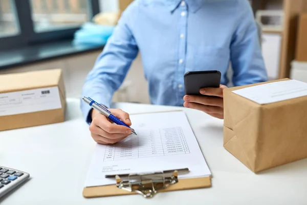 Femme avec smartphone et presse-papiers au bureau de poste — Photo