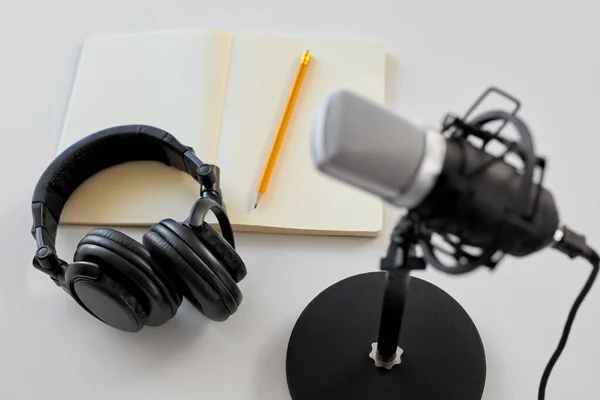 Headphones, microphone and notebook with pencil — Stockfoto