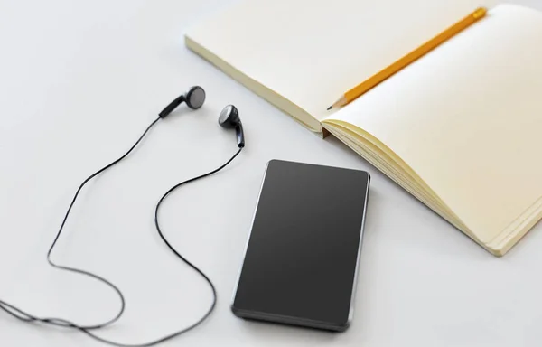 Earphones, smartphone and notebook with pencil — Stock Photo, Image