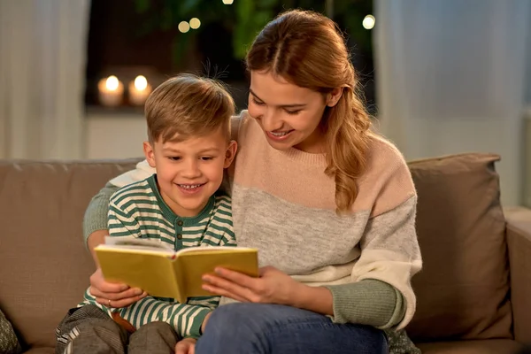 Gelukkig moeder en zoon lezen boek bank thuis — Stockfoto