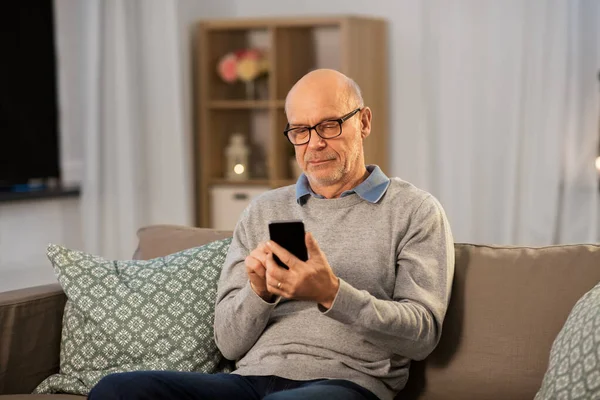 senior man texting on smartphone at home