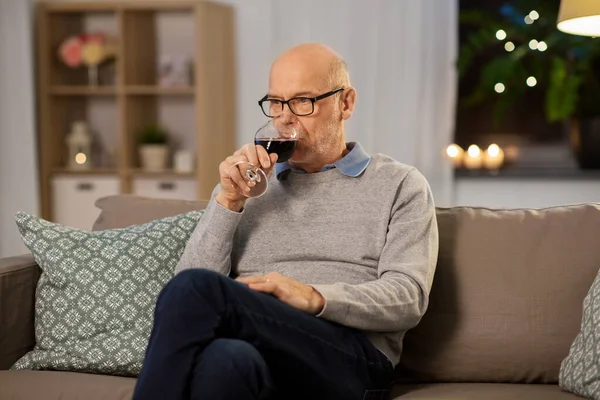 Ανώτερος άνθρωπος πόσιμο κόκκινο κρασί από το γυαλί στο σπίτι — Φωτογραφία Αρχείου