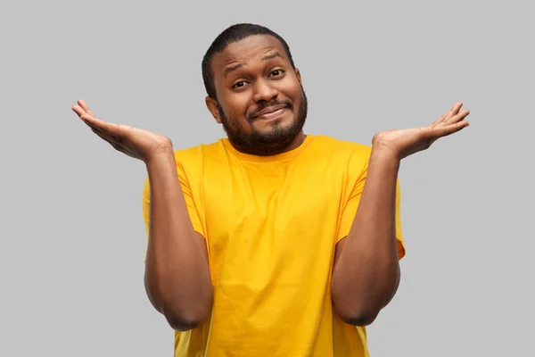 Afrikkalainen amerikkalainen mies keltaisessa t-paidassa kohauttelu — kuvapankkivalokuva