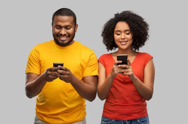 Feliz pareja afroamericana con teléfonos inteligentes — Foto de Stock