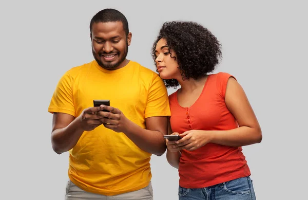 Feliz casal afro-americano com smartphones — Fotografia de Stock