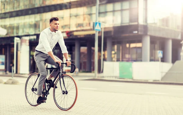 Человек с наушниками на велосипеде по улице города — стоковое фото