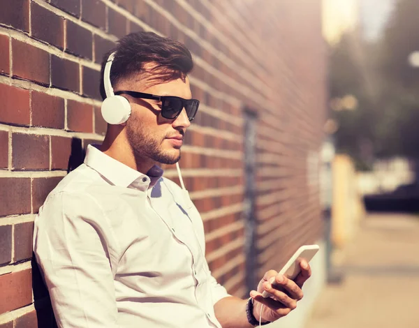 Man med hörlurar och smartphone lyssnar musik — Stockfoto