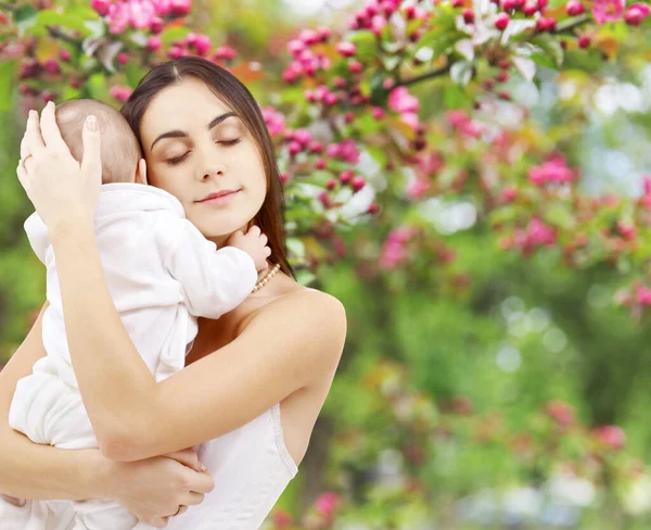 Mãe com bebê sobre o fundo do jardim primavera — Fotografia de Stock