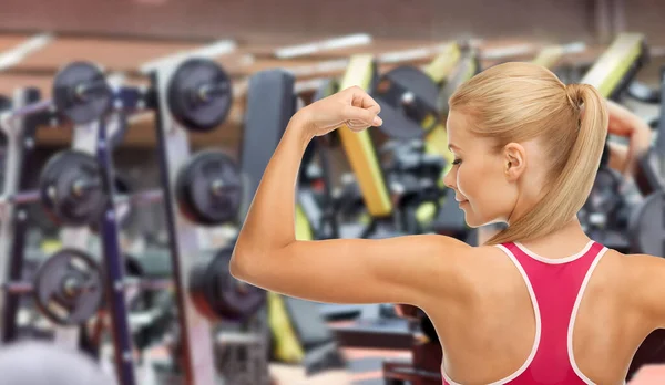 Jeune femme sportive montrant ses biceps dans la salle de gym — Photo