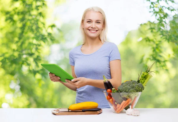 Smiling young woman with tablet pc cooking — Stock Photo, Image