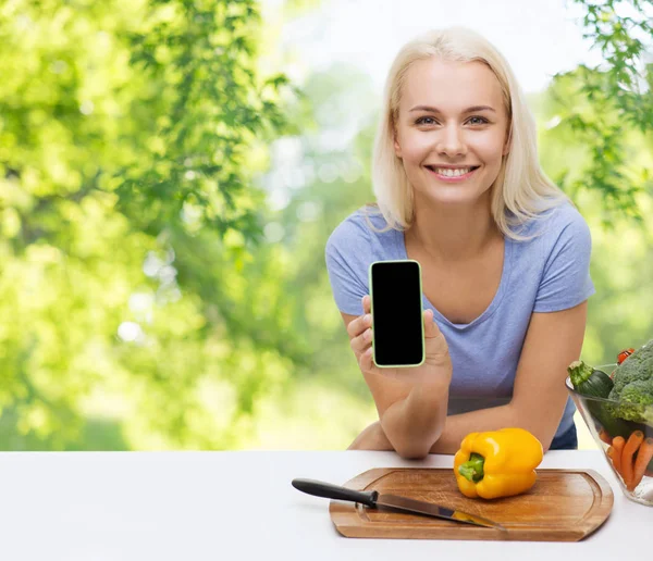 Lachende vrouw met smartphone koken groenten — Stockfoto